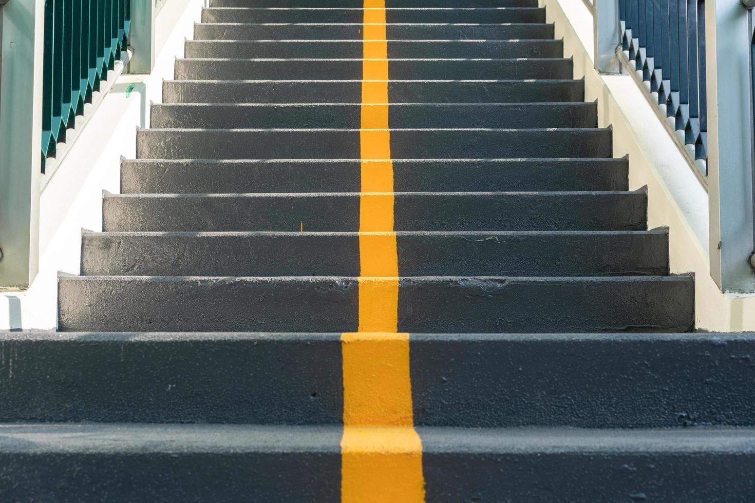 The stairway of the overpass with yellow line of lane and railing for road crossing safety. walk sign on ladder. Yellow cross on stairs. photo