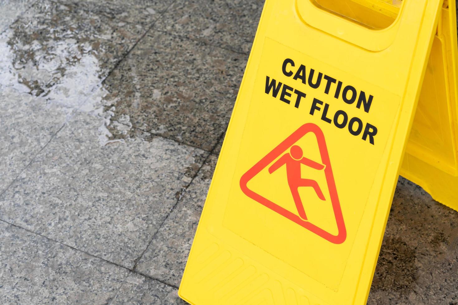 Yellow Caution slippery wet floor sign on the wet ground photo