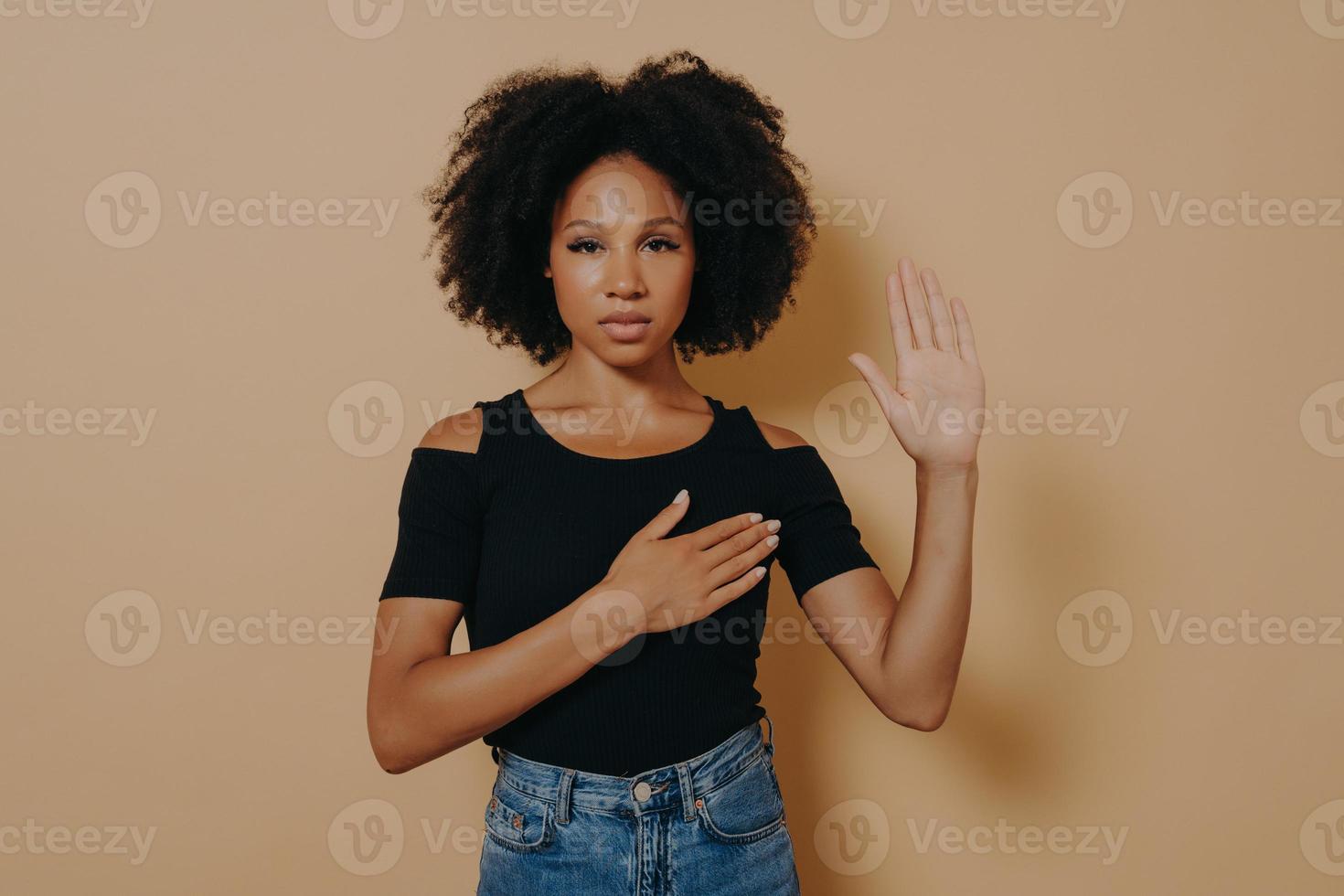 mujer de piel oscura con pantalones casual y jeans, haciendo juramento de promesa de lealtad foto