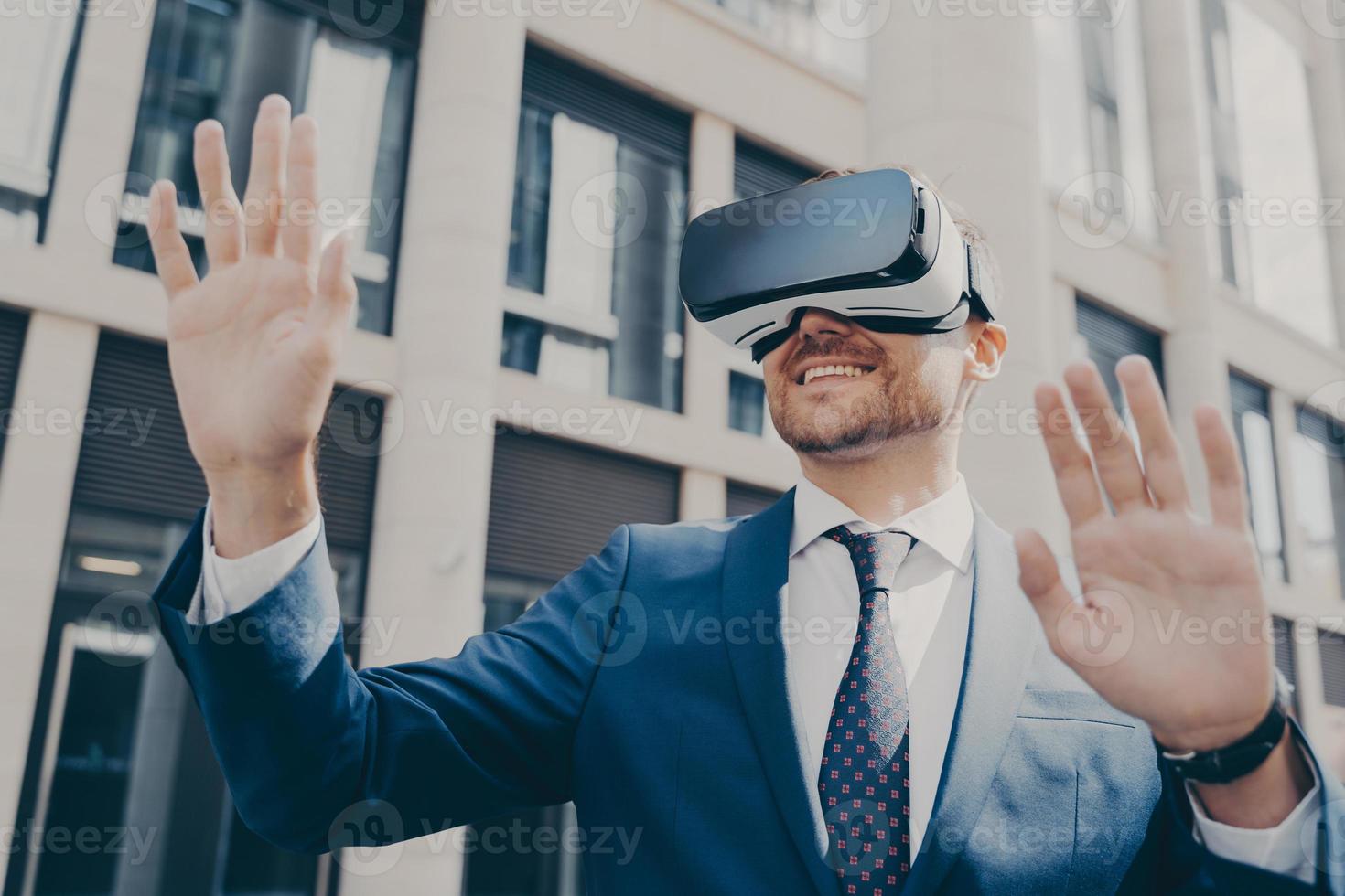 Professional impressed worker standing outside alone and using VR glasses to visualize projects photo