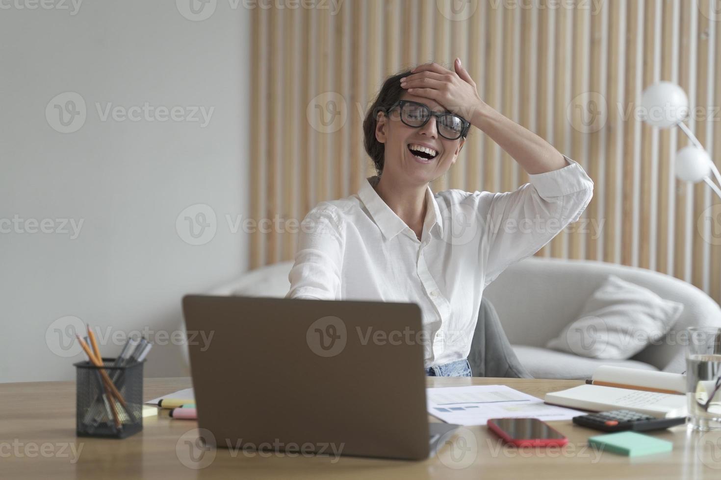 Happy overjoyed young Italian businesswoman receiving business offer by email on laptop photo