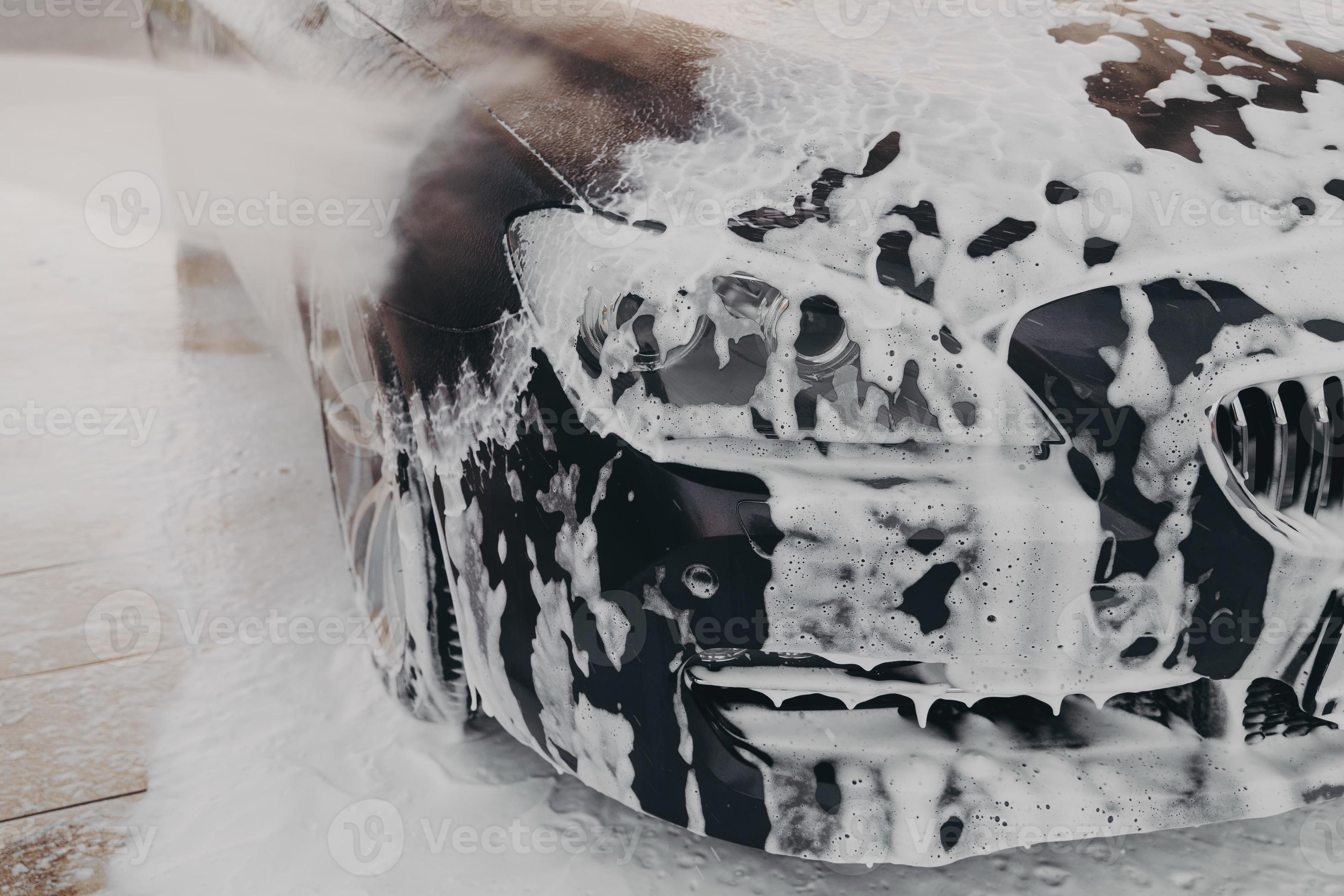 Black car in white snow foam during carwashing and cleaning outdoors 7485769 Stock Photo at Vecteezy