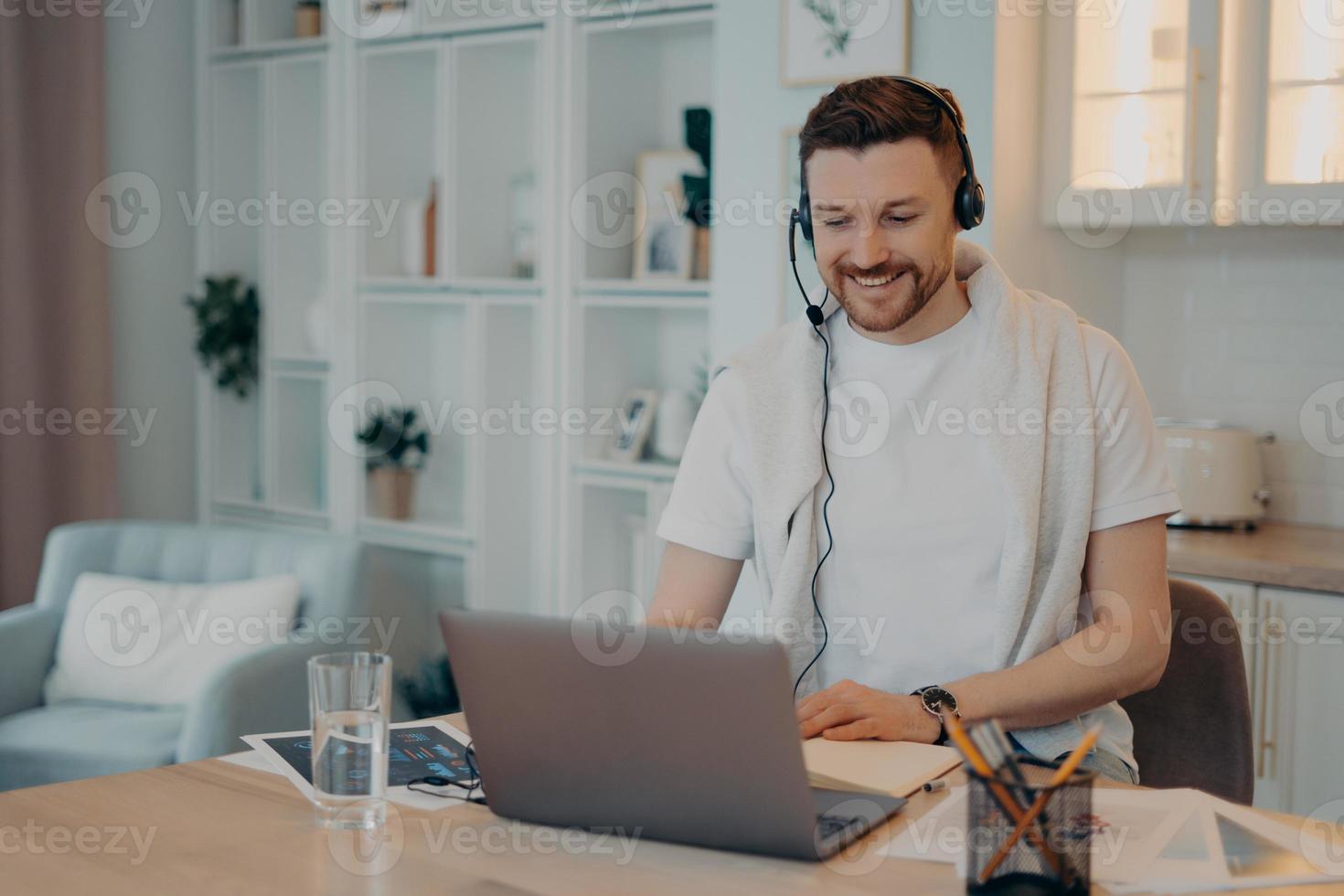 Male freelancer looking at laptop screen while working at home photo