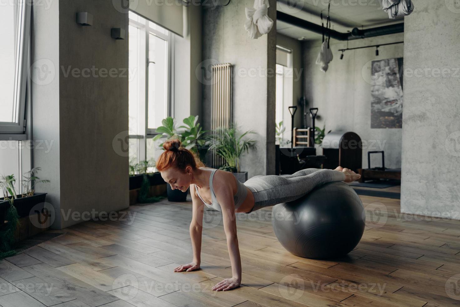 Happy healthy woman balancing on exercise ball during fitness workout photo