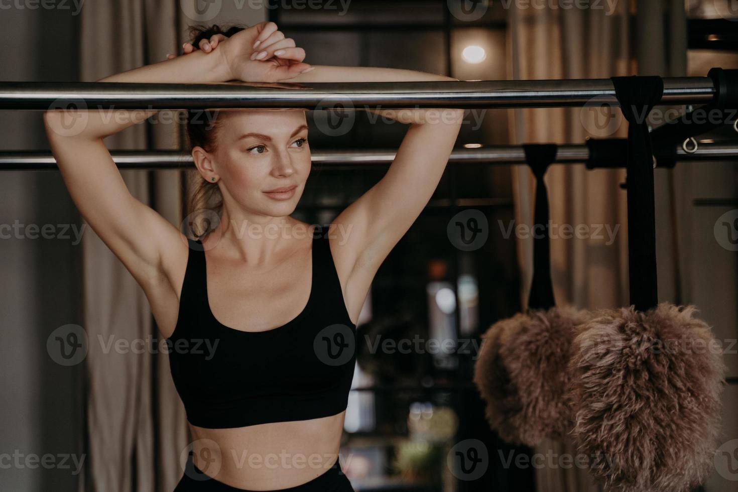 Young beautifull woman in leisure pose leaning forward on frame of pilates machine photo