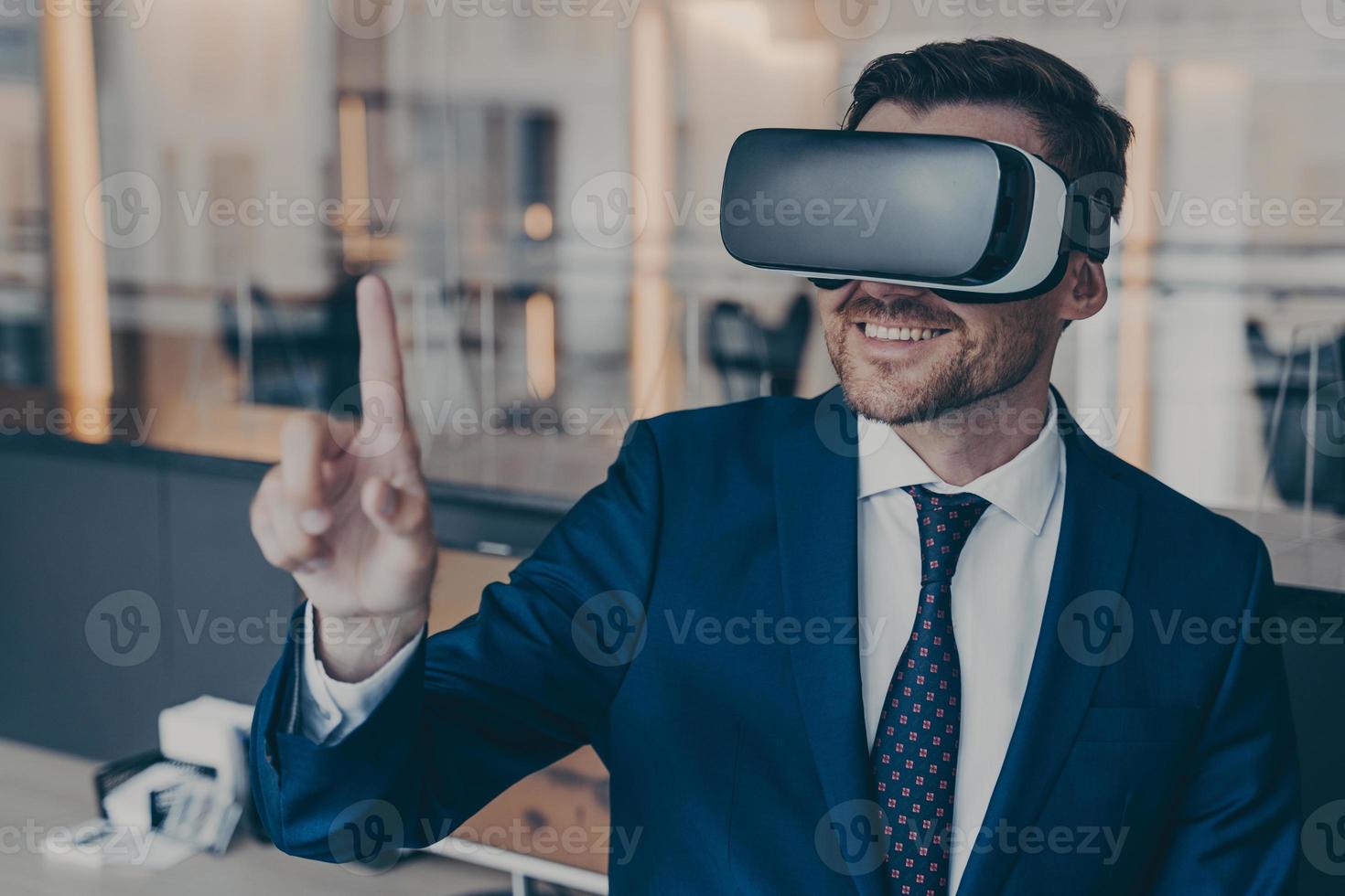 Smiling young finacier in formal suit enjoying spending time in virtual reality with VR headset photo