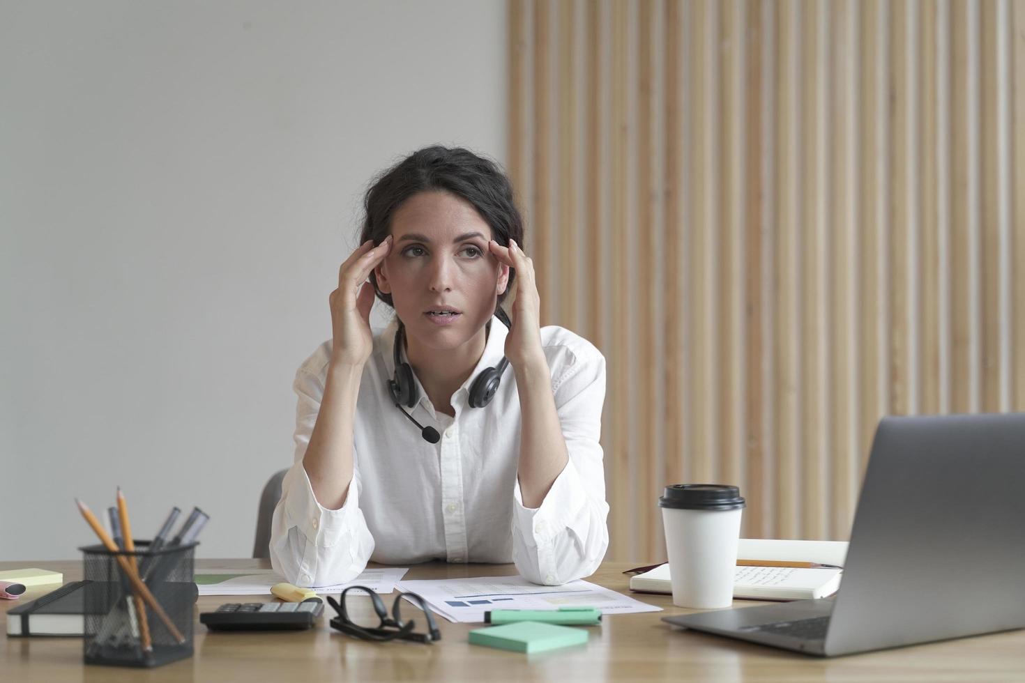 Frustrated businesswoman feeling tired while sitting in office, suffering from headache at work photo