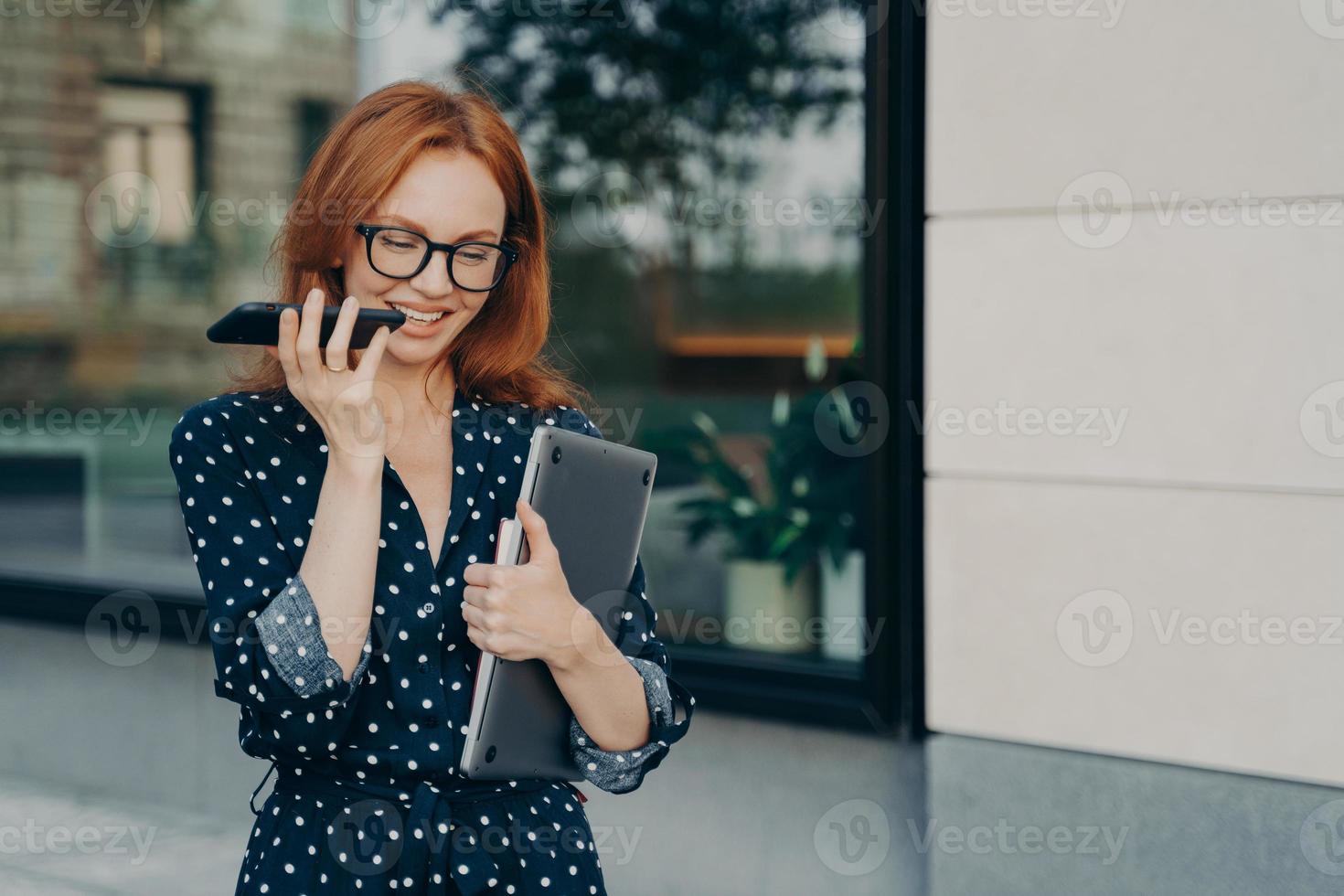 la empresaria camina al aire libre graba un mensaje de voz en las redes sociales a través de un teléfono inteligente foto