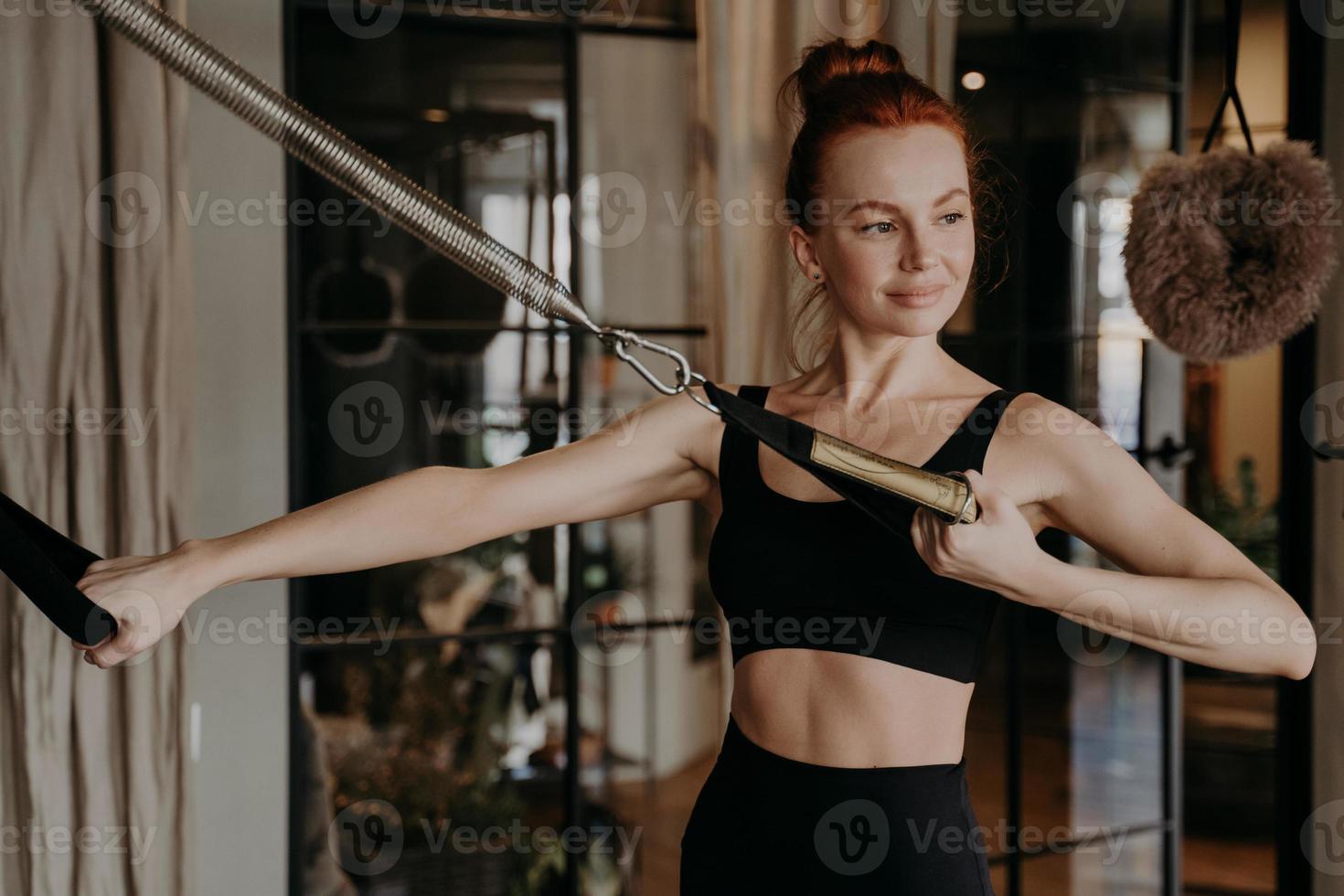 tiempo de entrenamiento de una mujer pelirroja sana y feliz, haciendo ejercicio en el reformador de cadillac foto