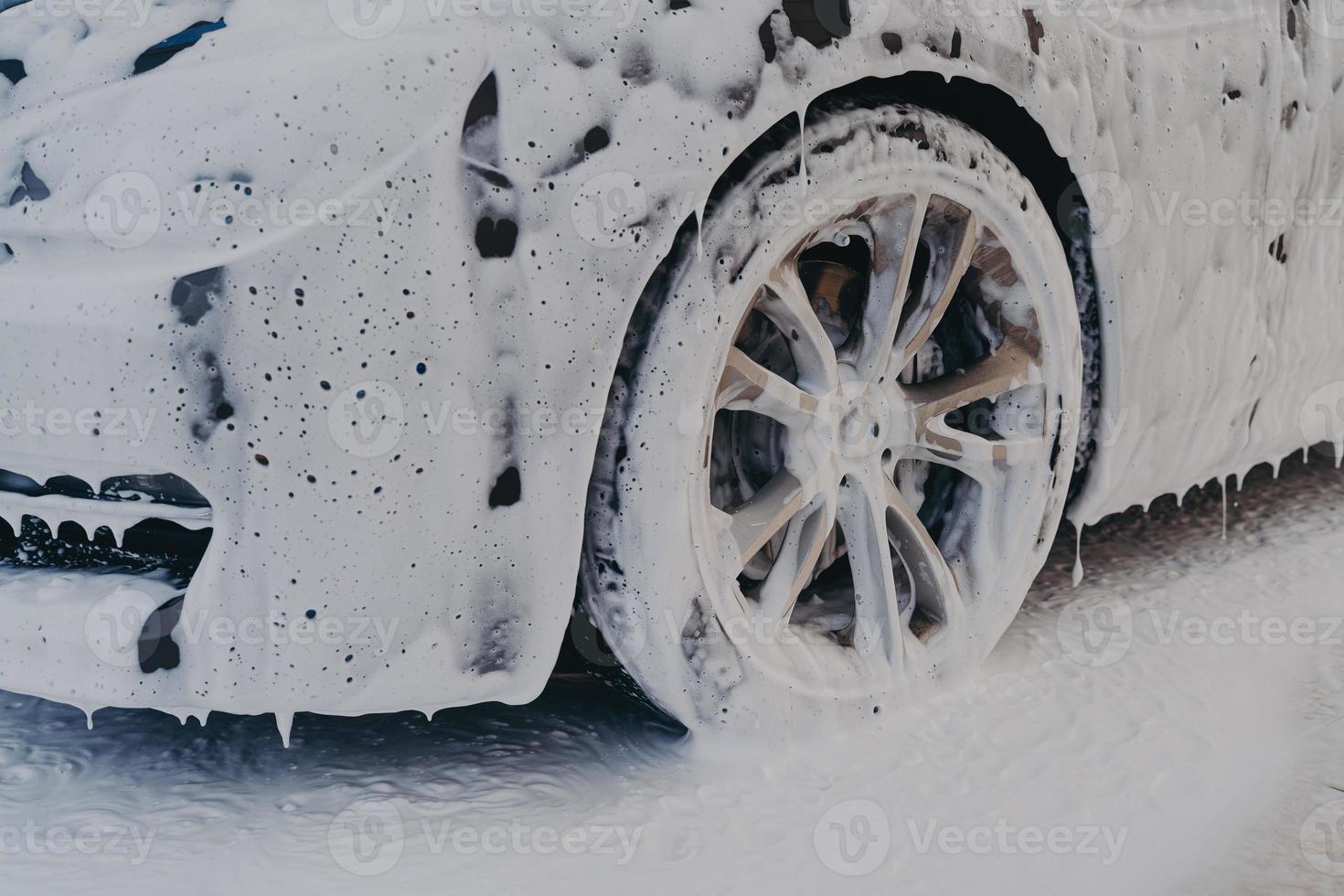rueda de coche en espuma de jabón blanco en la estación de servicio de lavado de coches foto