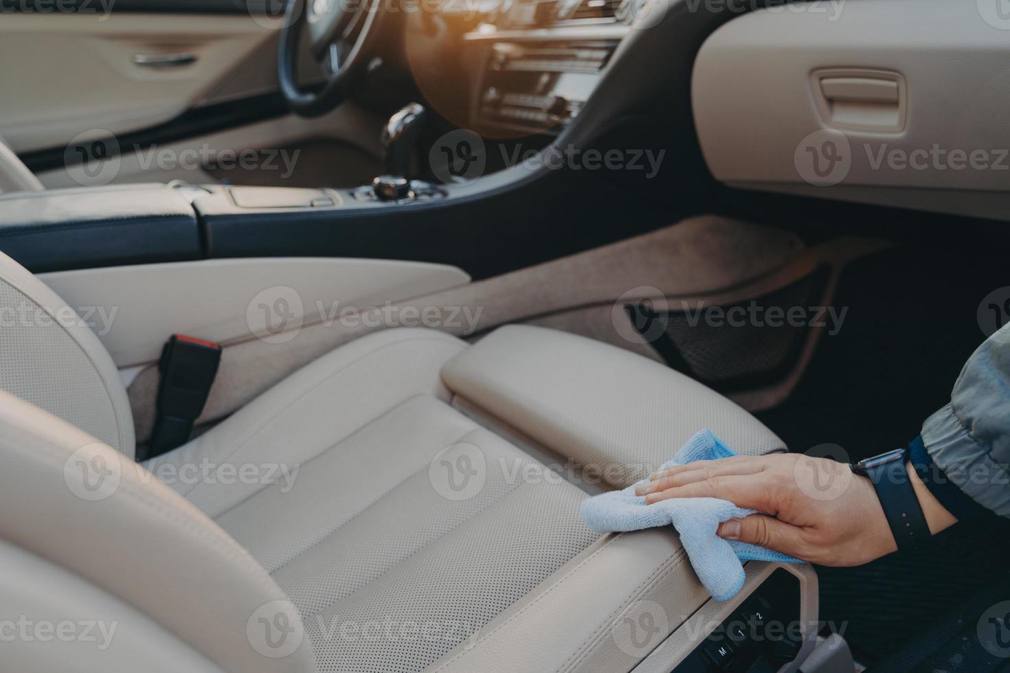 Male hand disinfecting fabric car seat with microfiber cloth photo