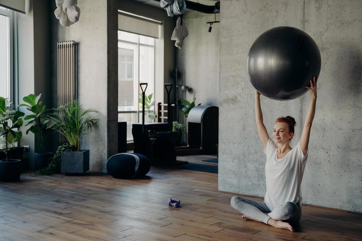 Smiling woman in lotus position enjoying pilates or fitness workout indoors photo