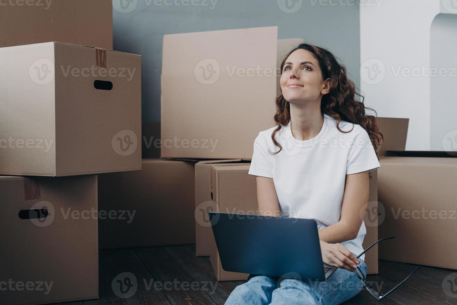 Hopeful hispanic woman sitting among cardboard boxes and chatting online. Romantic relationship. photo