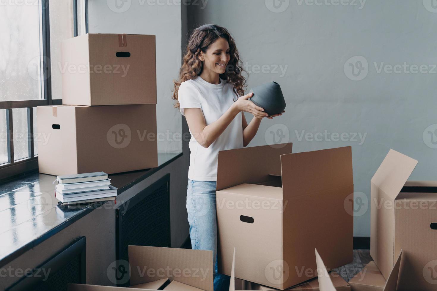 Happy girl unpacking cardboard boxes and taking the vase. European