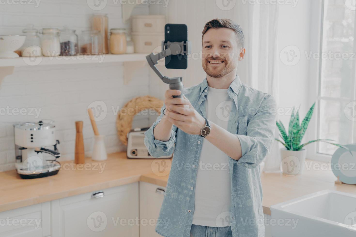 Young man blogger recording video blog with mobile phone at home photo