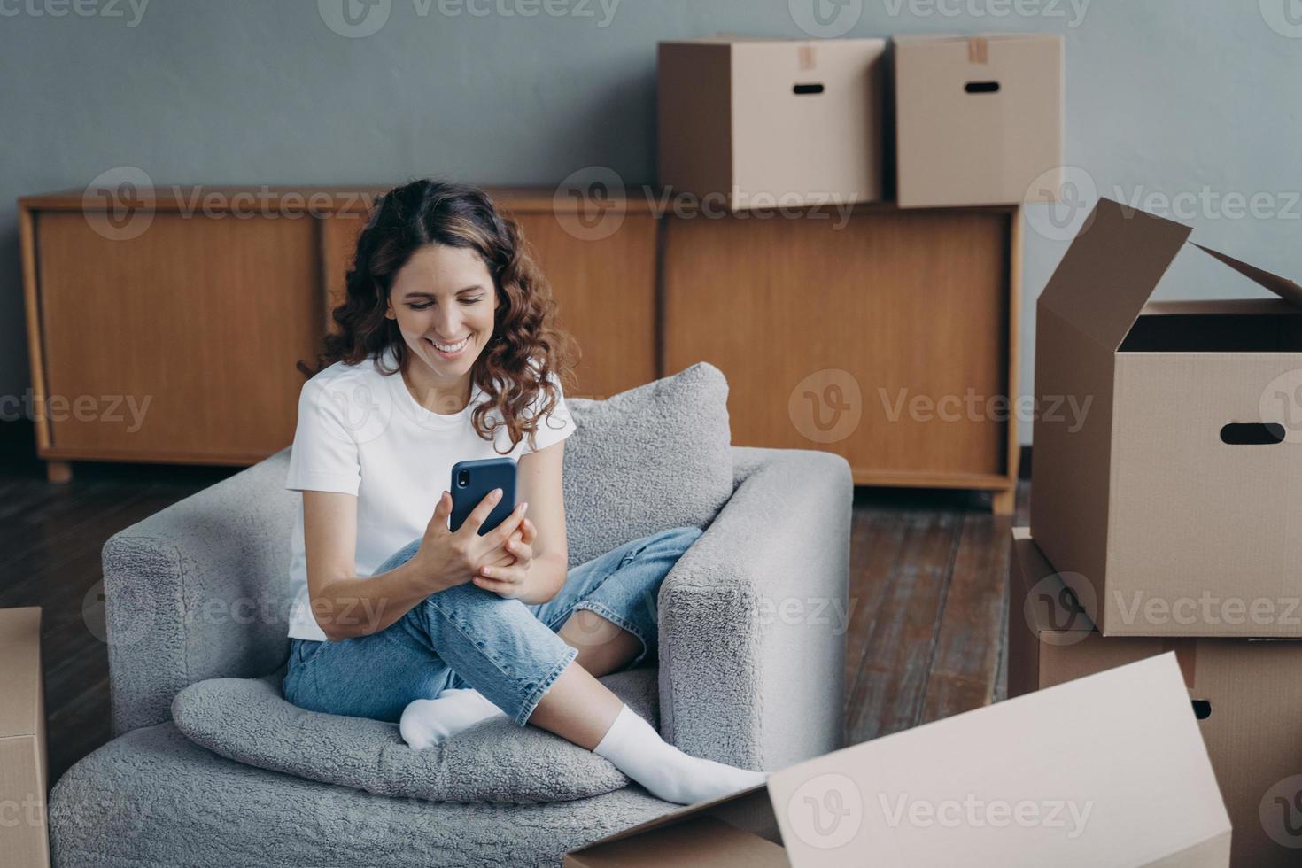 la mujer satisfecha se está moviendo. la niña hace clic en el teléfono y solicita el servicio de entrega mediante la aplicación. foto