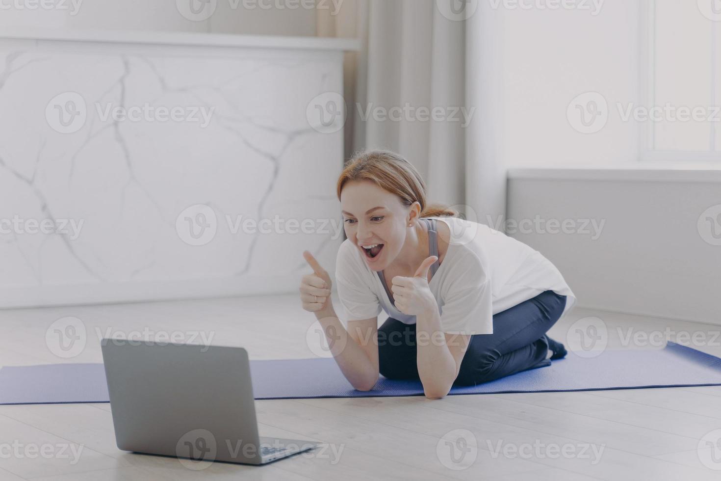 European white woman has distance sport classes. Girl gestures thumbs and feels good. photo