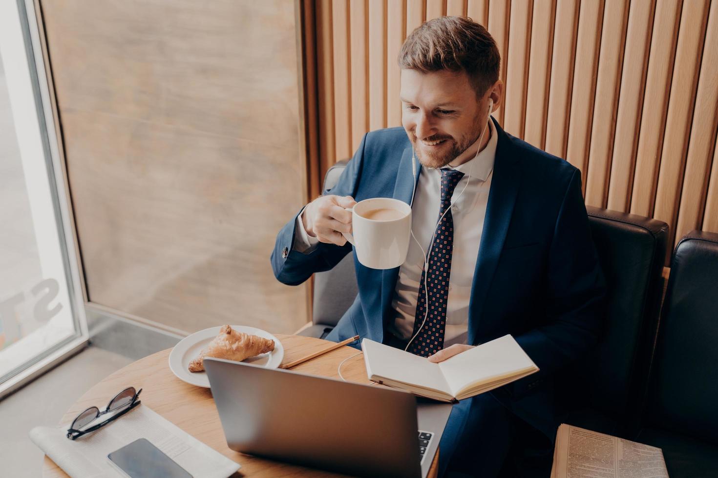 Attractive businessman remotely working online while sitting in coffee shop photo