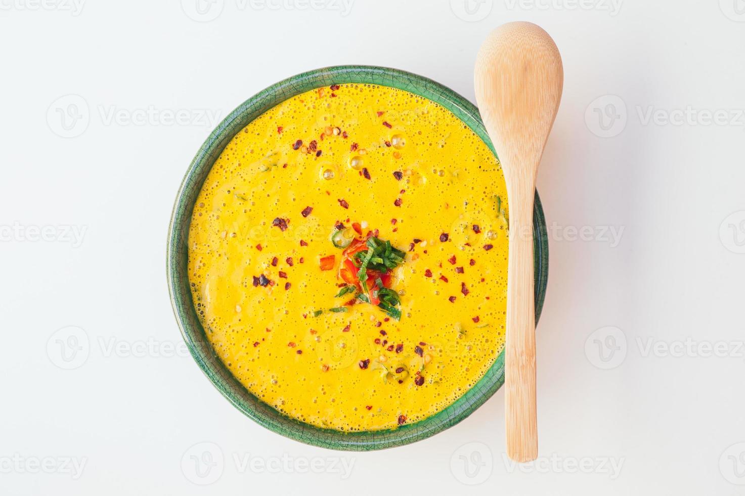 Top view of fresh delicious pumpkin soup with wooden spoon. Tasty dinner for you. Green curry on white background. Healthy nutrition concept. Creamy tasty soup. photo