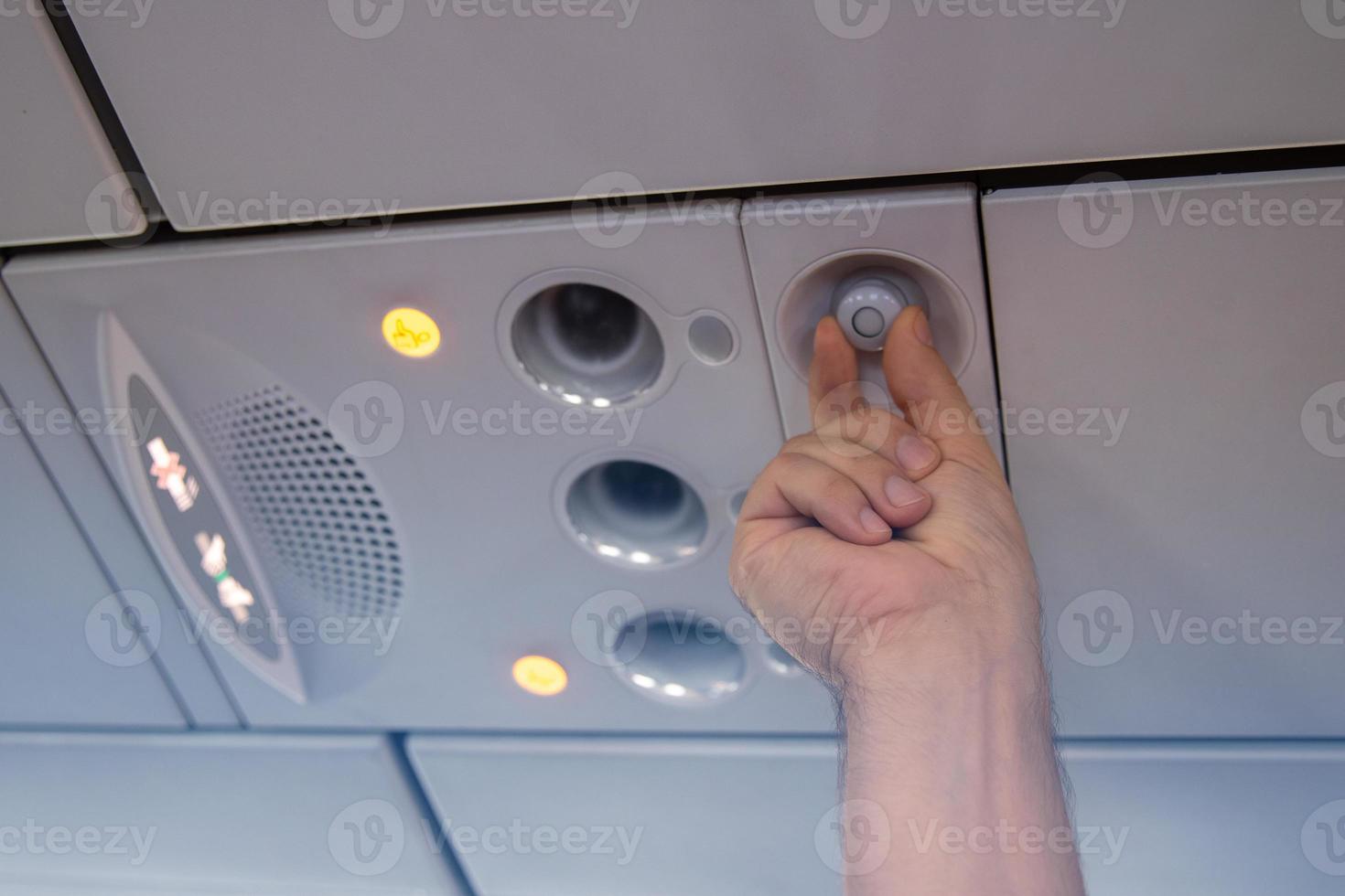 Hand man up to adjust console panel. The air condition, light, low cost airline seat. While on board of an aircraft, selective focus. Blur background color vintage style. photo