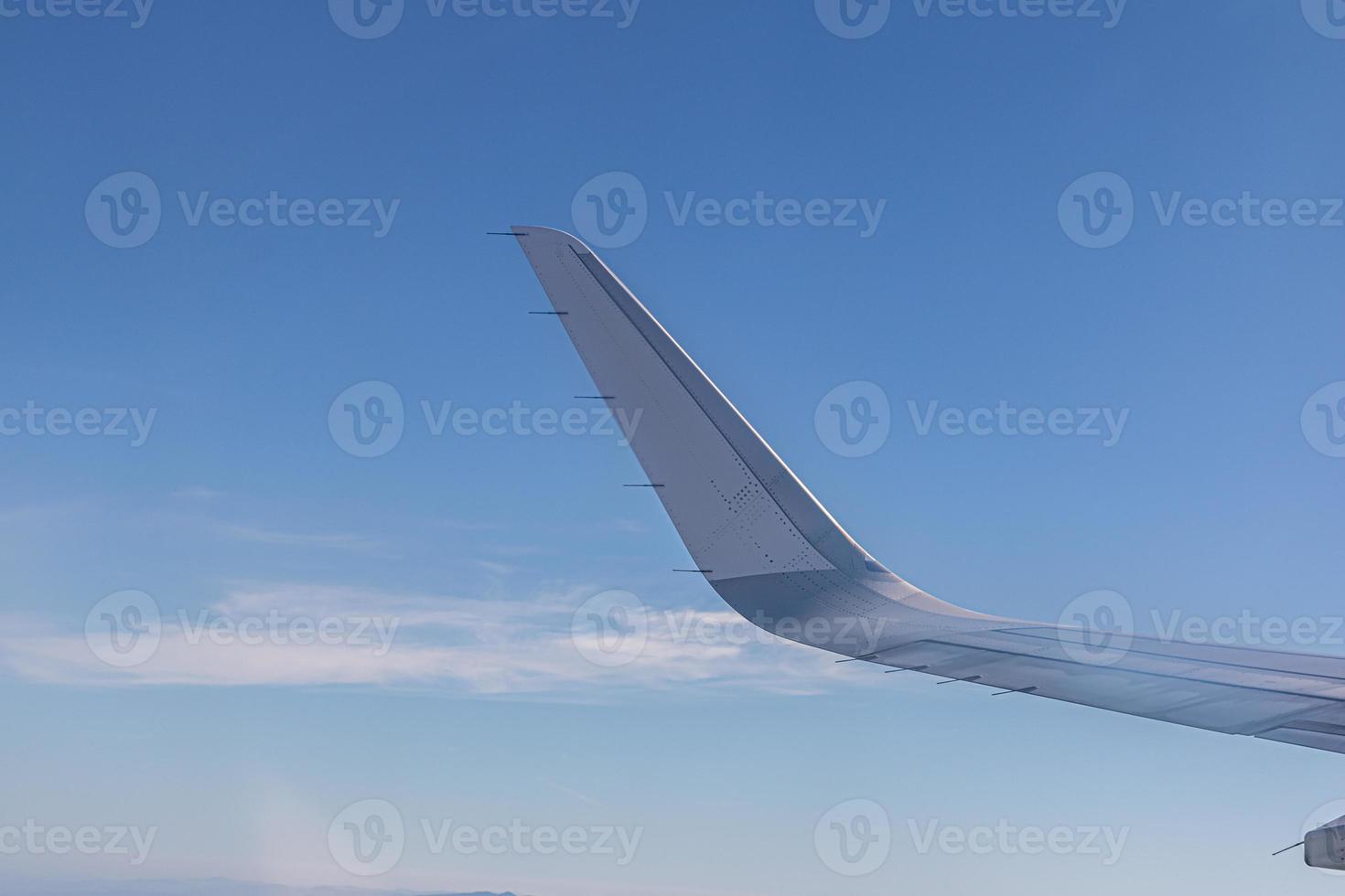 Wing of plane with beautiful sunrise skyline. Airplane flying on blue sky. View from airplane window. Commercial airline flight in the morning with sunlight. Plane wing above clouds. photo