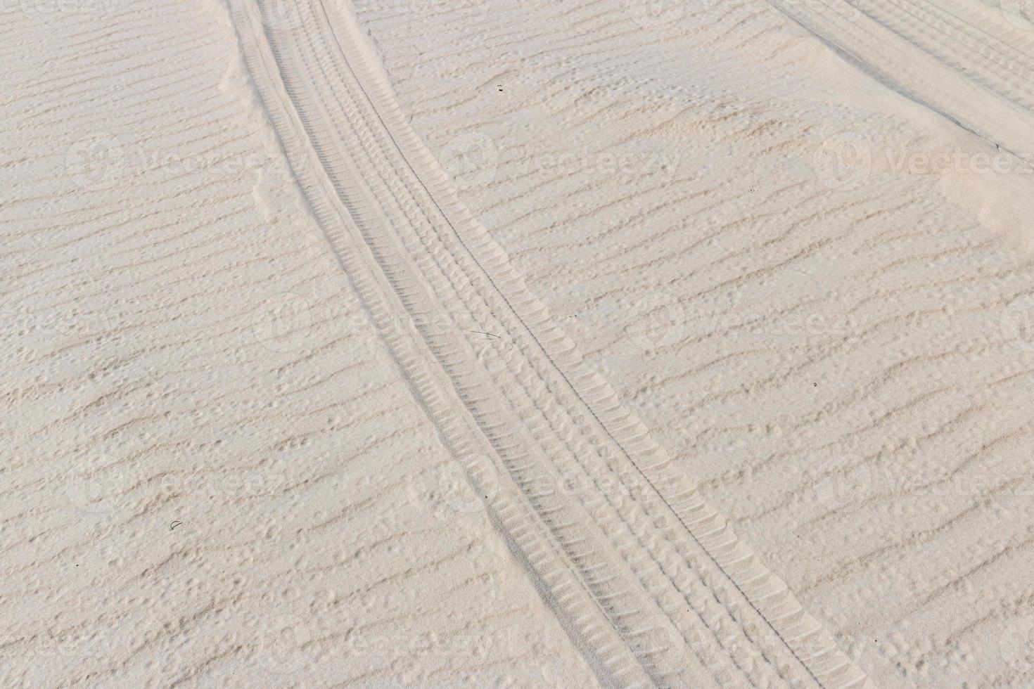 Tire trail in the sand of dunes on the beach or desert. photo