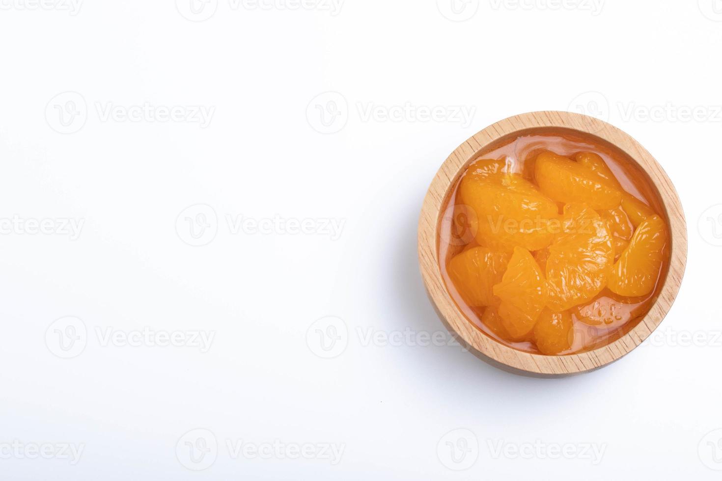 naranjas peladas en escabeche en almíbar en una taza.sobre un fondo blanco. foto
