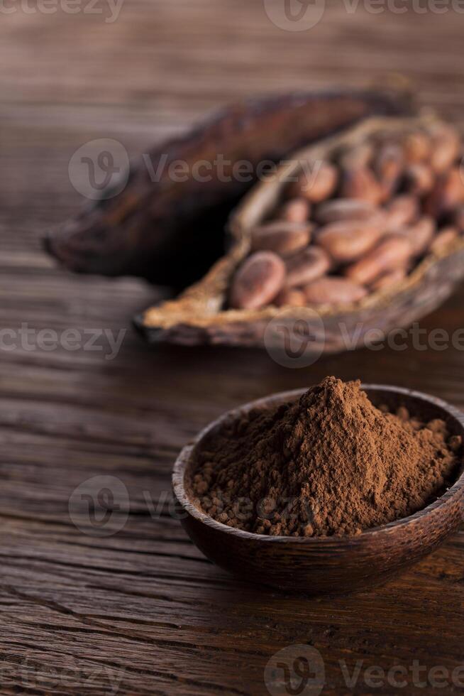 granos de cacao en la fruta seca de la vaina de cacao sobre fondo de madera foto