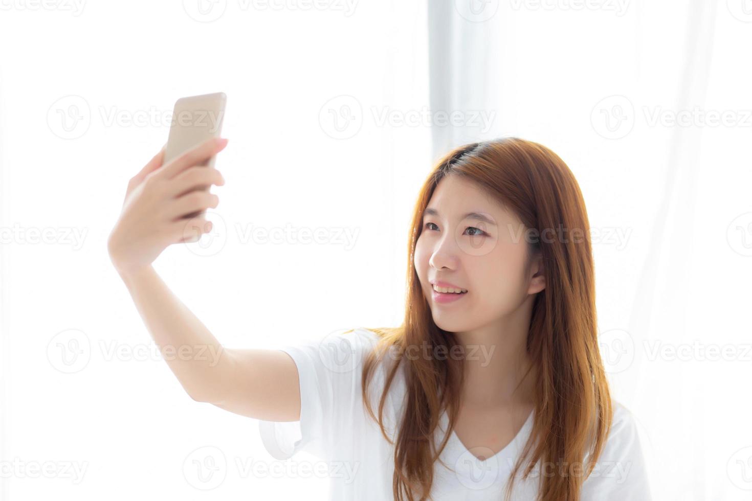 hermoso retrato joven mujer asiática tomando un selfie con teléfono móvil inteligente en el dormitorio, la chica está fotografiando con felicidad y sonrisa con diversión, concepto de estilo de vida. foto