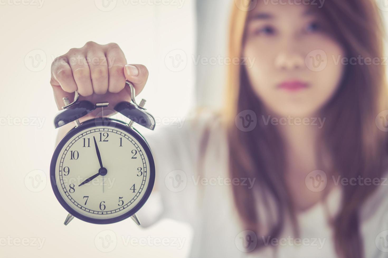 Beautiful asian young woman wake up in morning annoyed alarm clock holding hand, girl hurry wake late with appointment, lifestyle concept. photo