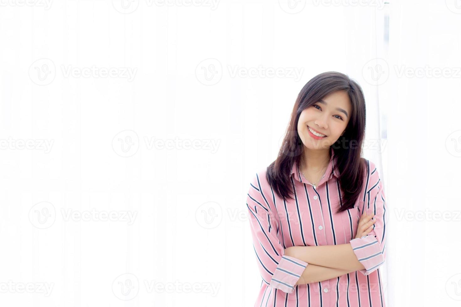 Portrait of beautiful young asian woman standing the window and smile while wake up with sunrise at morning, lifestyle and relax concept. photo