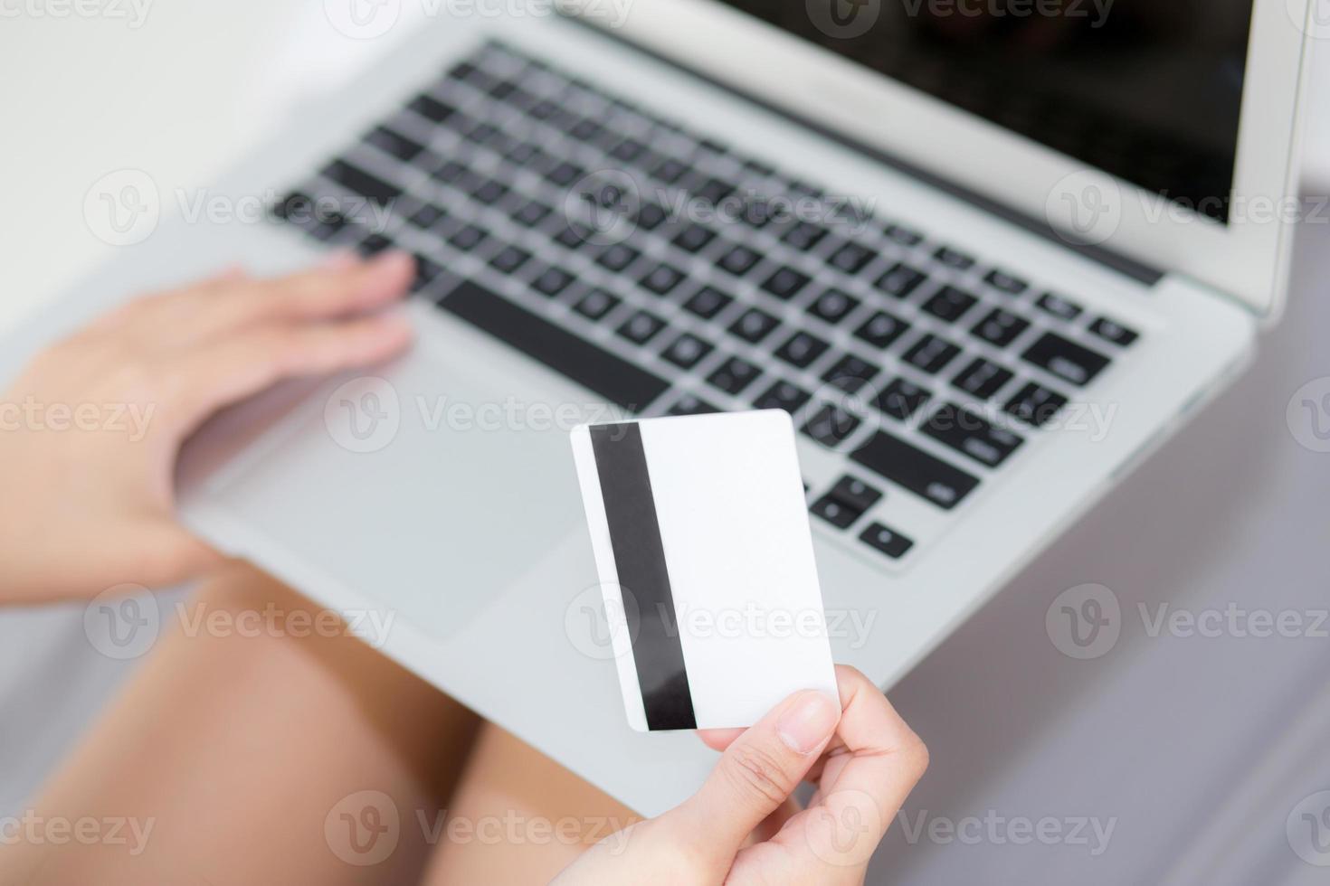 mano sosteniendo una tarjeta de crédito usando una computadora portátil comprando en línea para el comercio electrónico web, comprando y pagando dinero con tarjeta de débito, finanzas y concepto de compra. foto