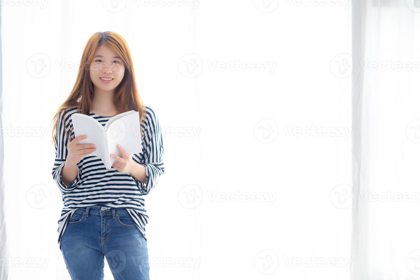 Beautiful of portrait young asian woman relax standing reading book on bedroom at home, girl study literature, education and lifestyle concept. photo