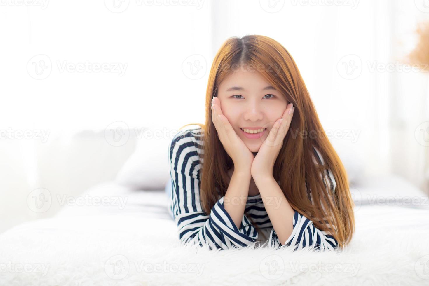 Beautiful portrait young asian woman lying and smile while wake up with sunrise at morning, lifestyle and relax concept. photo