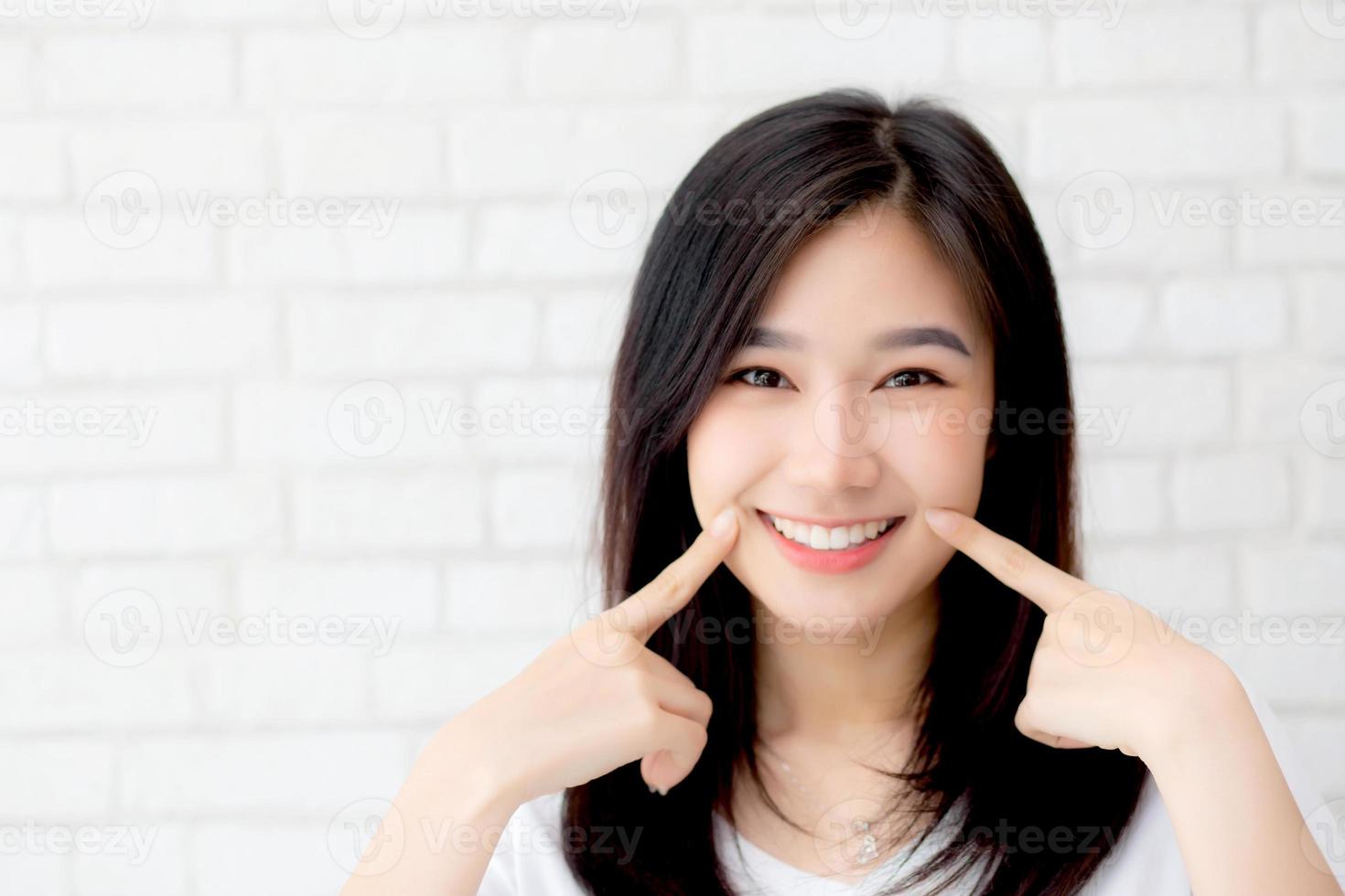 Portrait of beautiful young asian woman happiness standing finger touch cheek on gray cement texture grunge wall brick background, businesswoman is a smiling on concrete, business people concept. photo