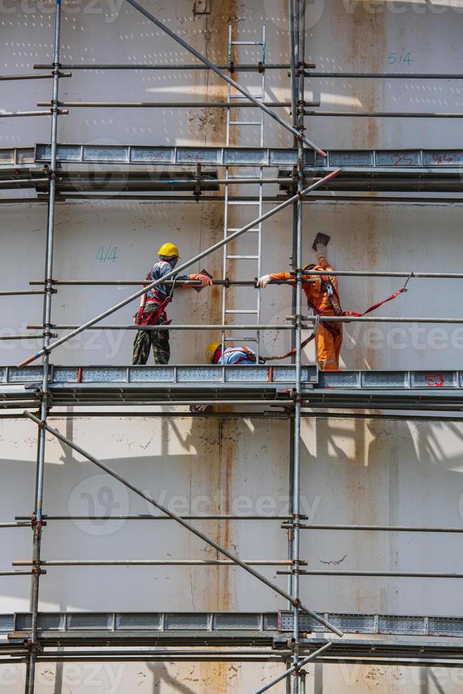 Construction workers tank oil installing scaffolding photo