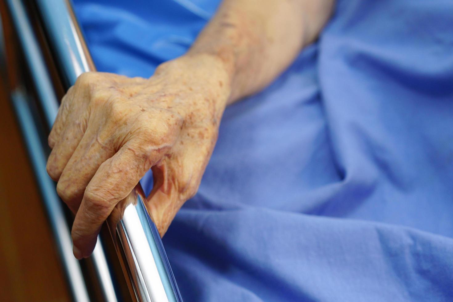 The hands of a senior or elderly old woman patient as grab at the edge of the bed. Healthcare and medical concept. photo