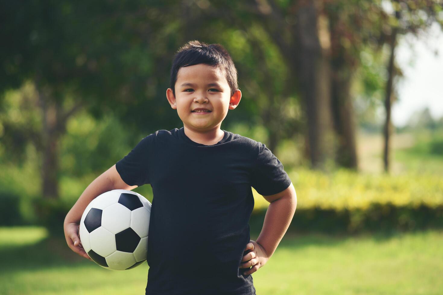 niño pequeño mano sujetando fútbol soccer foto