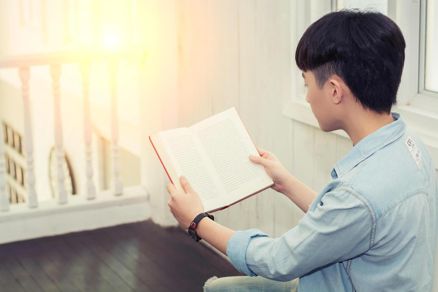 young man reading book and sitting on straw in the farm photo