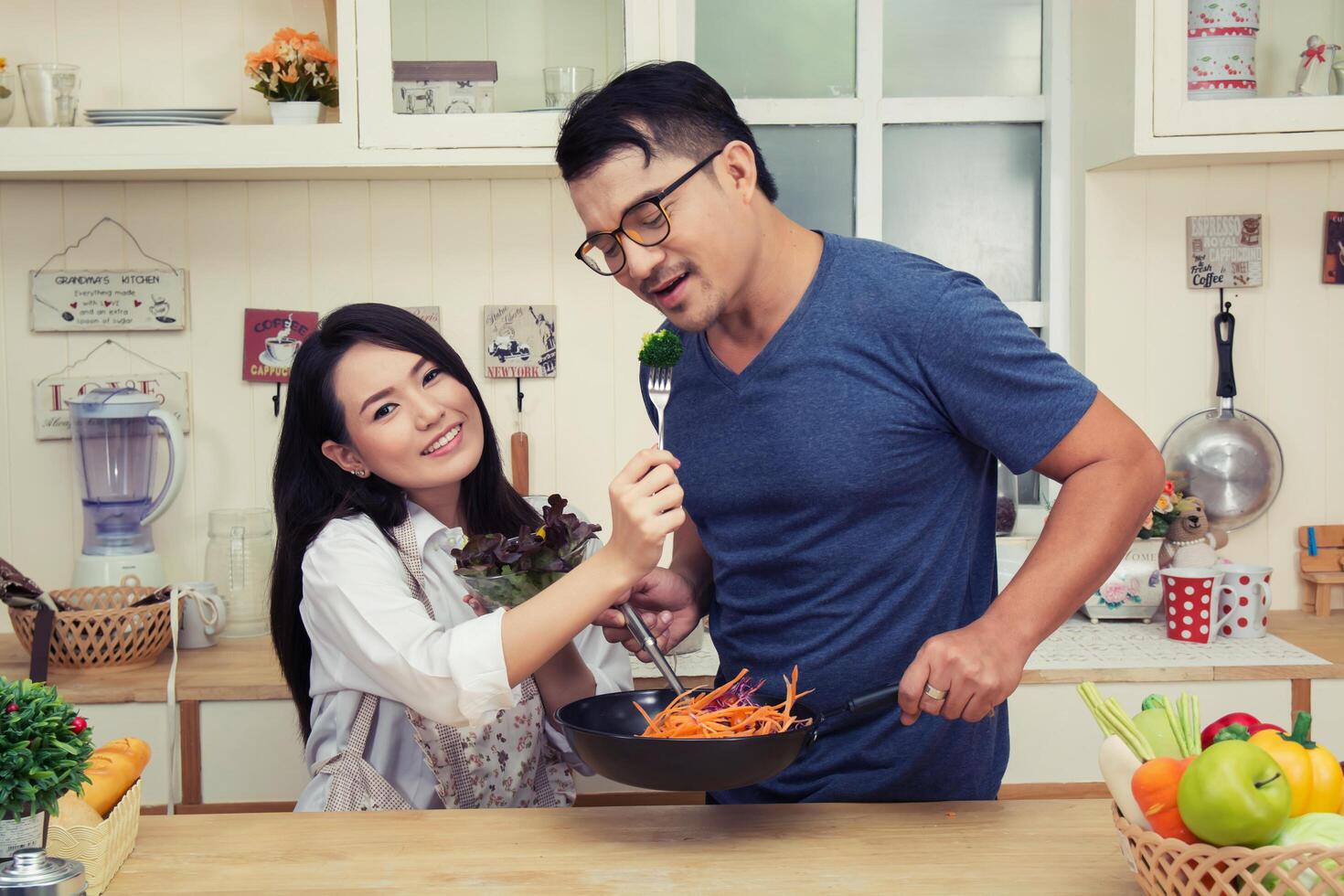 Happy couple Eating vegetable. Having fun in the kitchen. photo