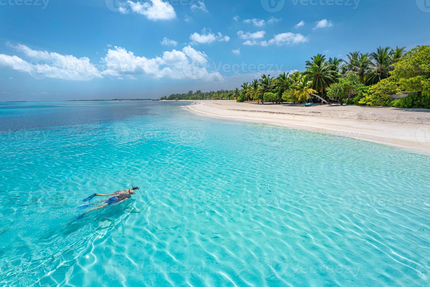 Caucasian couple of tourists snorkel in crystal turquoise water near Maldives Island. Perfect weather conditions at luxury resort beach scene, calm sea water, couple exotic water, underwater wildlife photo