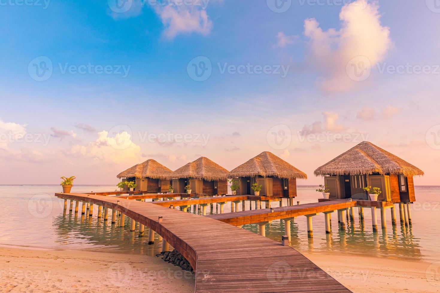 Maldives island sunset. Water bungalows resort at islands beach. Indian Ocean, Maldives. Beautiful sunset landscape, luxury resort and colorful sky. Artistic beach sunset under wonderful sky photo