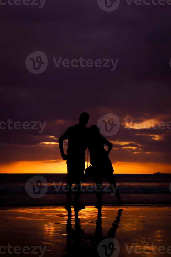 silueta de pareja tomándose de la mano y feliz pareja joven amor en la playa al atardecer foto