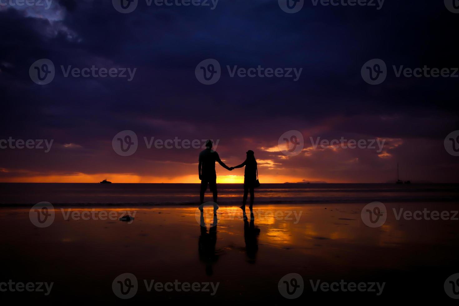 Silhouette of couple hold each other hand and Happy Young Couple love on the beach at sunset time photo