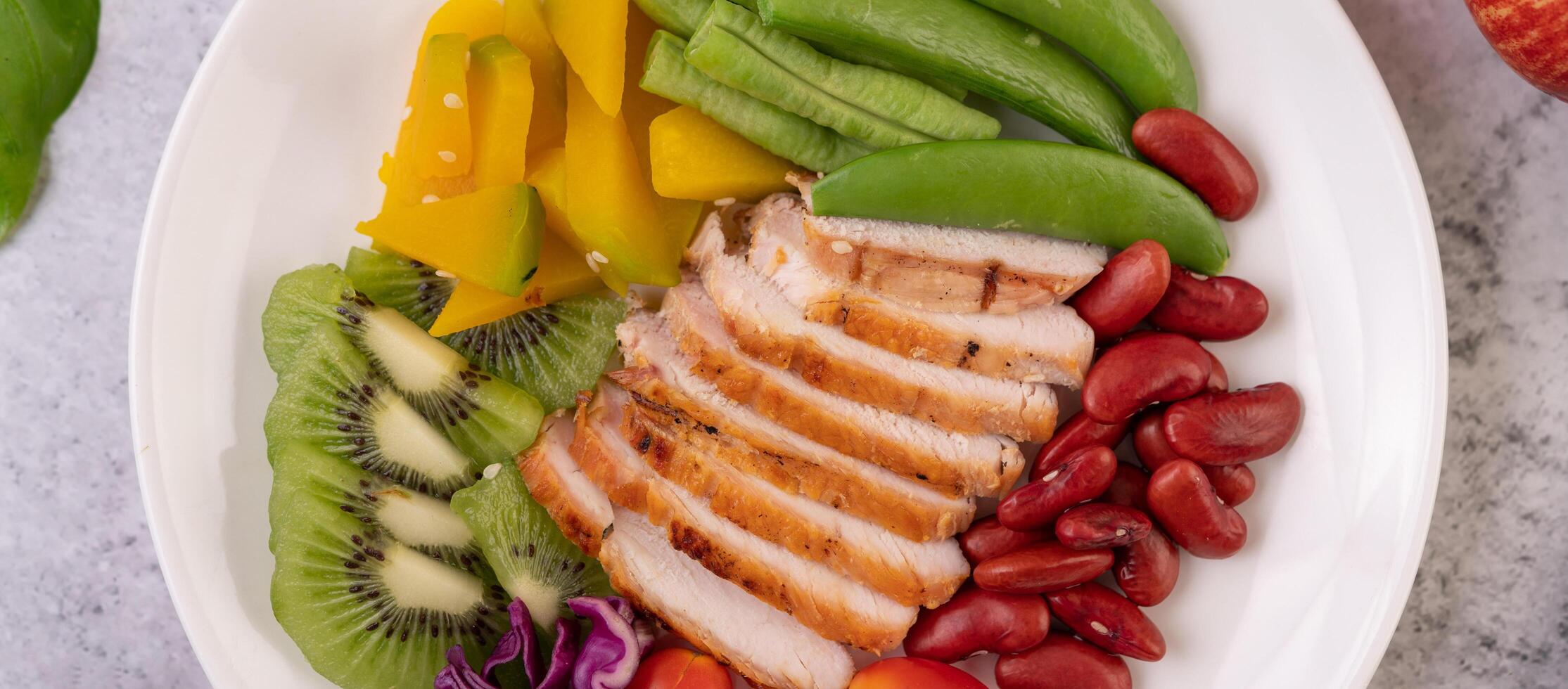 Chicken steak with peas, tomatoes, kiwi and pumpkin. photo