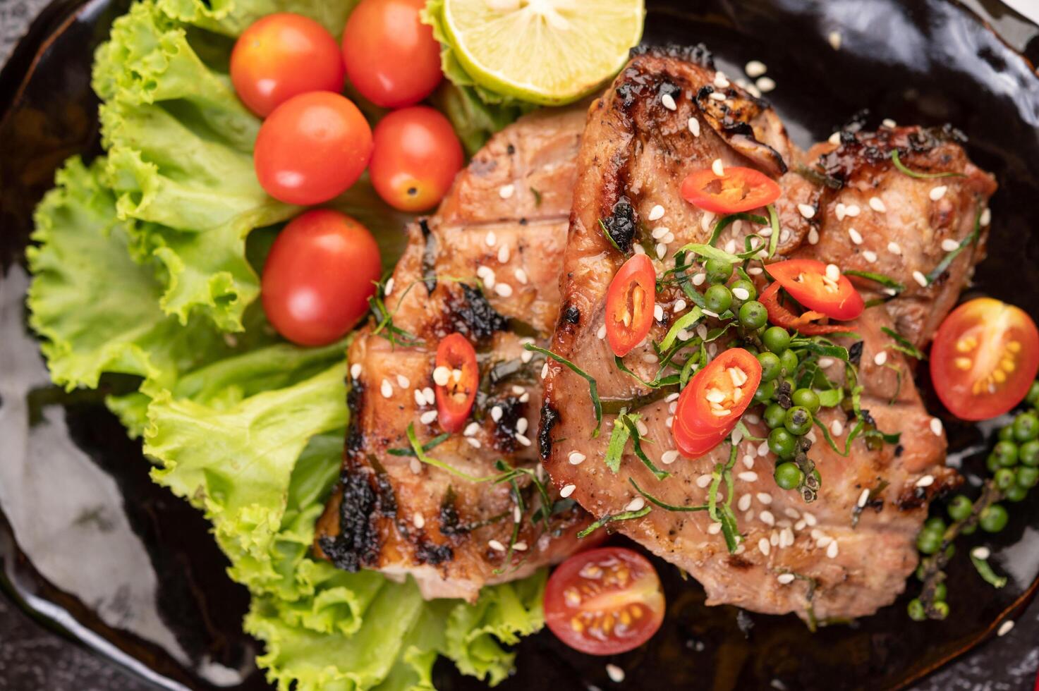 Pork steak topped with white sesame and fresh pepper seeds along. photo