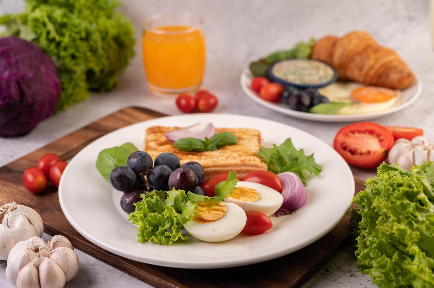 el desayuno consiste en pan, huevos cocidos, aderezo para ensalada de uva negra, tomates. foto