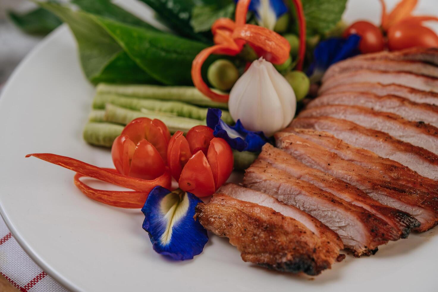 Pork with lemon, onion, red onion, tomato, long bean, butterfly pea flower, and mint. photo