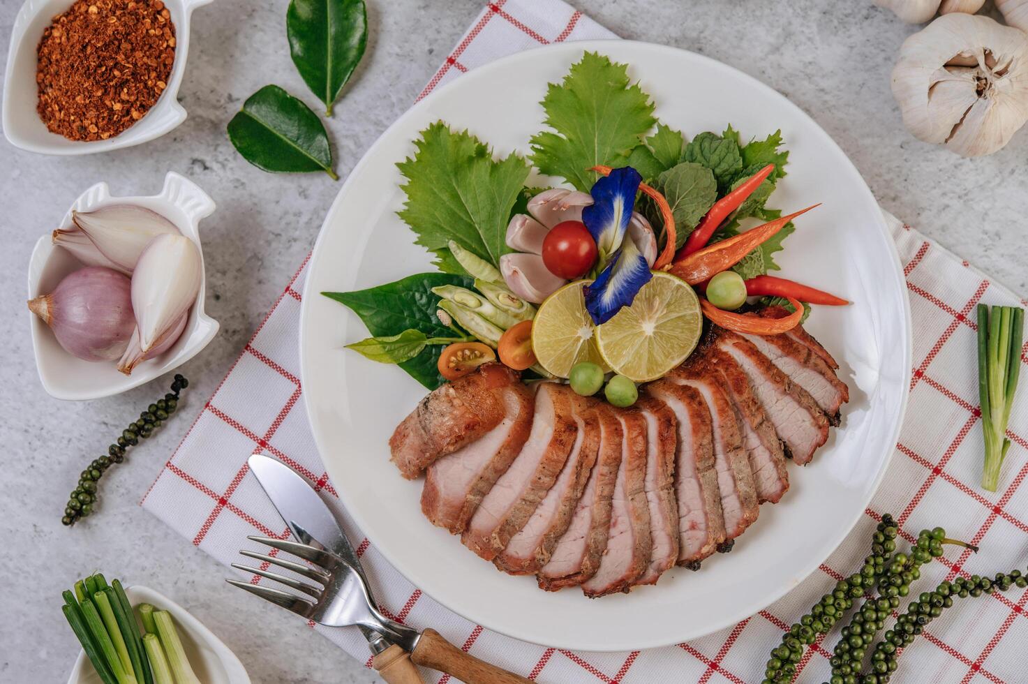 Pork with lemon, onion, red onion, tomato, long bean, butterfly pea flower, and mint. photo