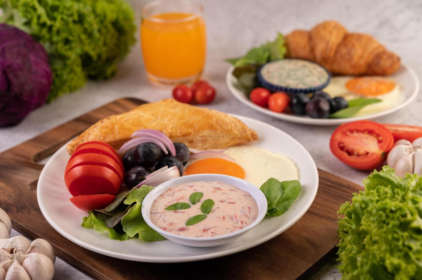 Breakfast consists of bread, fried egg, salad dressing, black grapes, tomatoes. photo